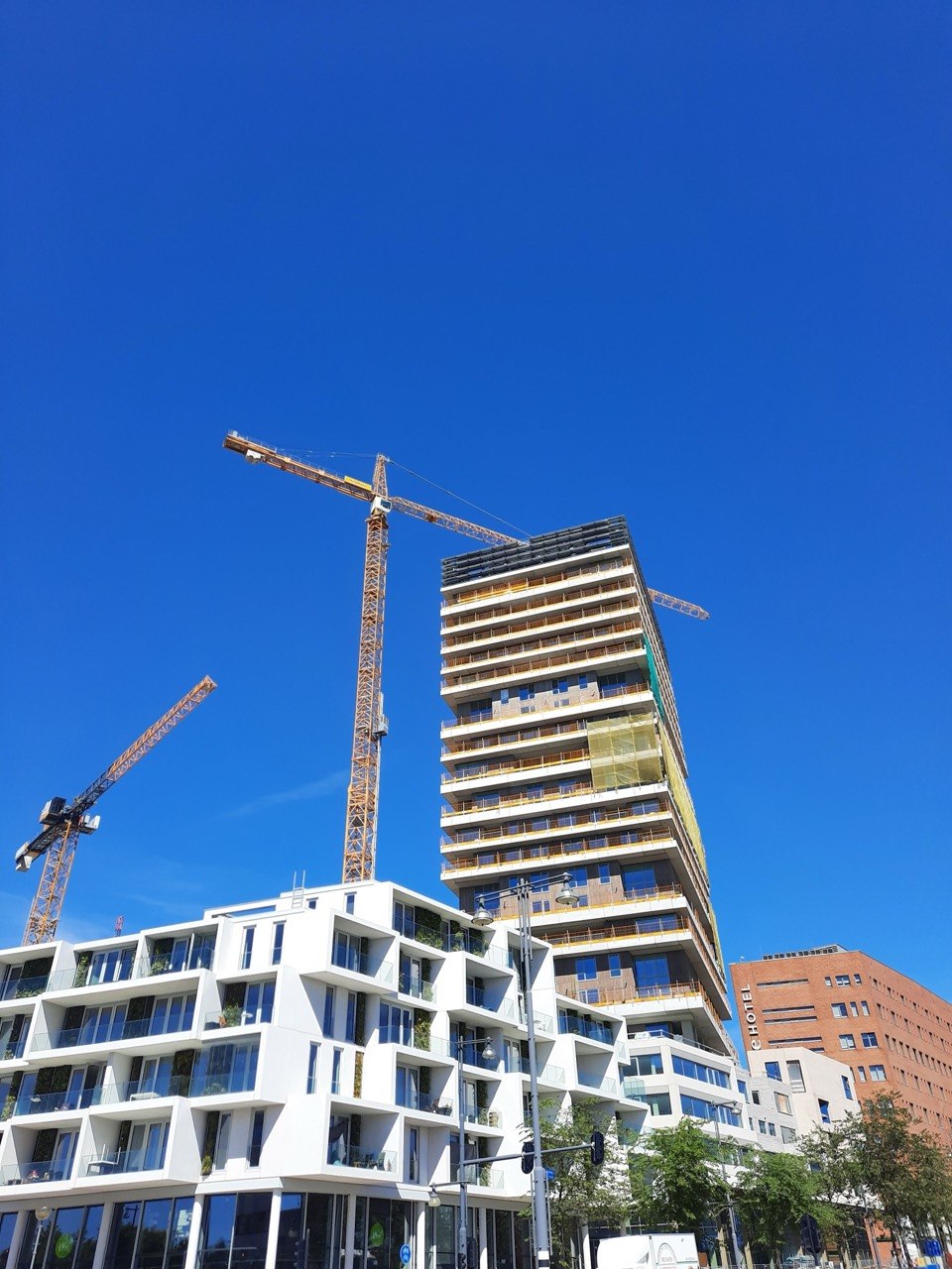 Bouwtoren en bouwkranen onder een blauwe lucht